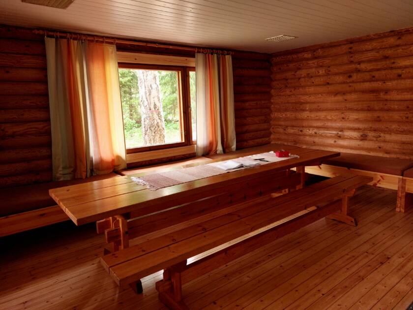 Saunatupa ja ikkuna sisältäpäin, seinustalla penkkejä, keskellä puinen pitkä pöytä.