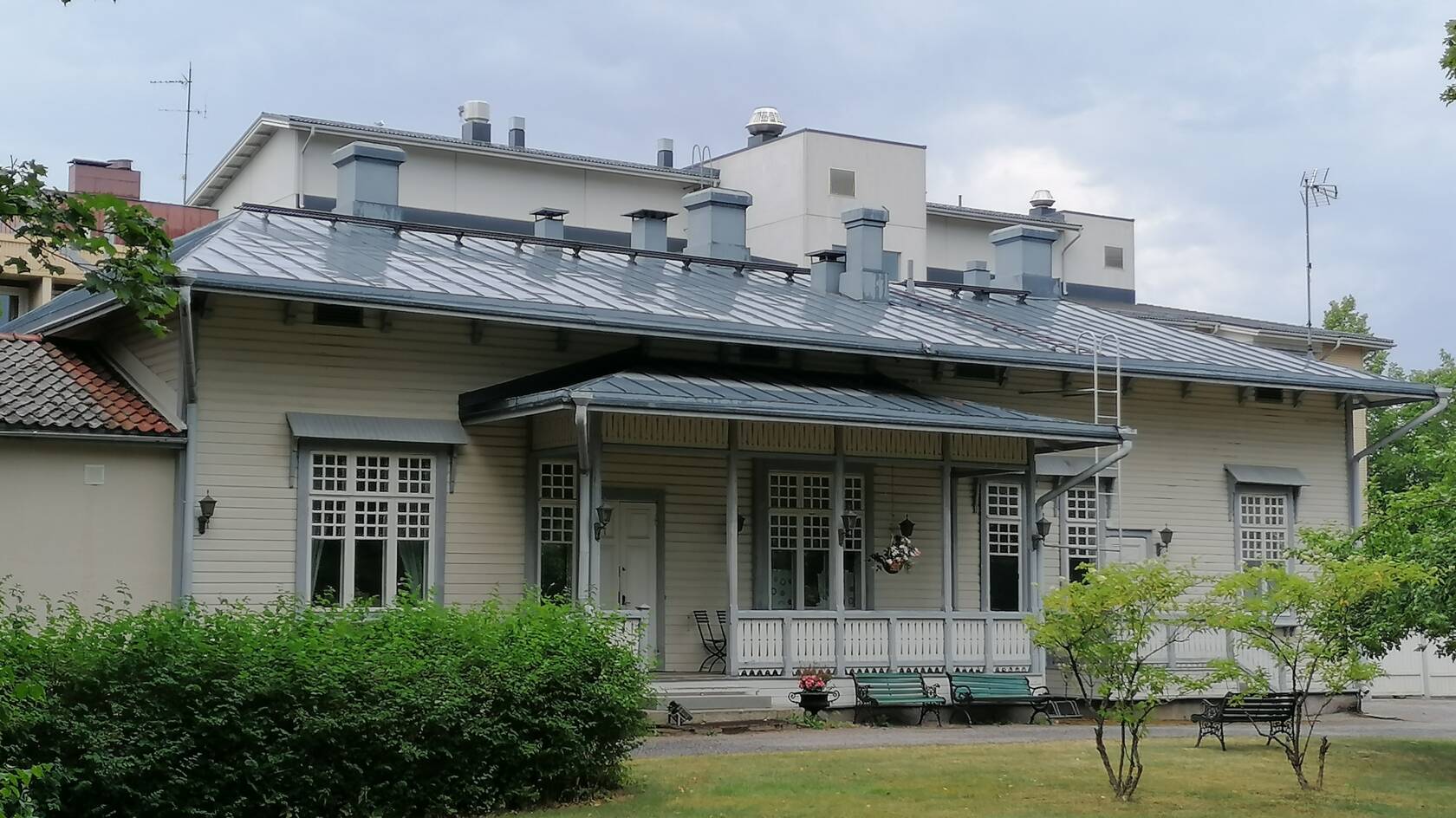 Vanha pappila on vaalea koristeellinen puurakennus 1900-luvun alusta. Ympärillä puistoa.