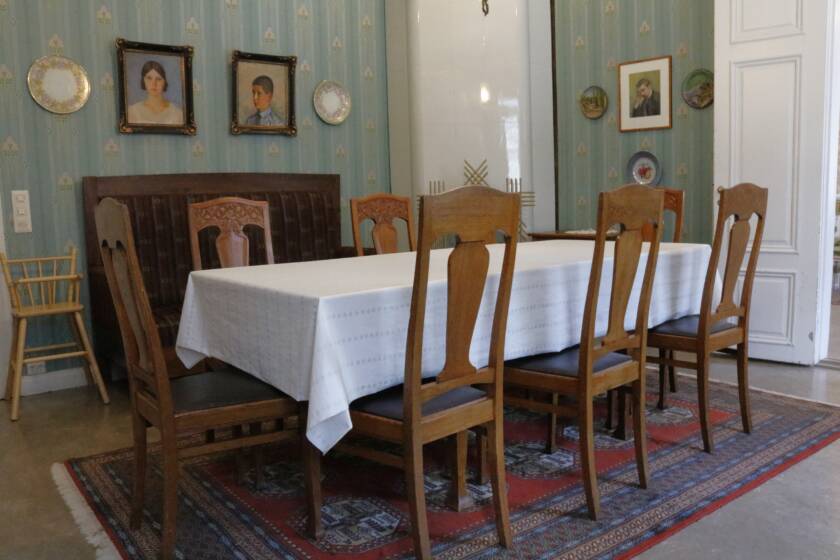 Ruokasalissa on pitkä pöytä ja koristeelliset tammituolit kahdeksalle. Seinillä koristeellinen tapetti ja muotokuvia,