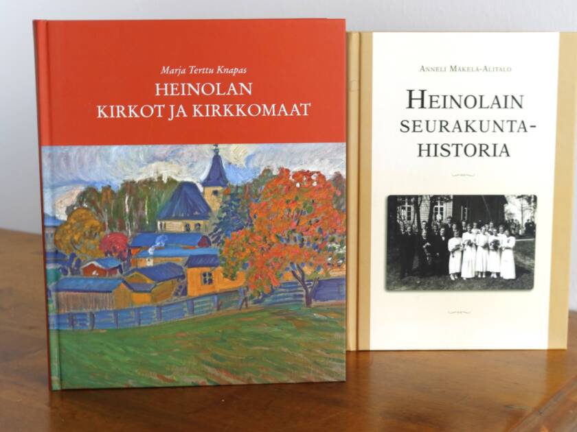Kaksi kirjaa pystyssä hyllyllä. Marja-Terttu Knapas: Heinolan kirkot ja kirkkomaat sekä Anneli Mäkelä-Alitalo: Heinolain seurakuntahistoria.