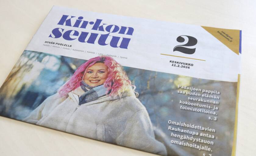 Kirkonseutu-sanomalehti pöydällä. Kannessa kuva hymyilevästä naisesta, jolla on vaalea takki ja pinkit hiukset.