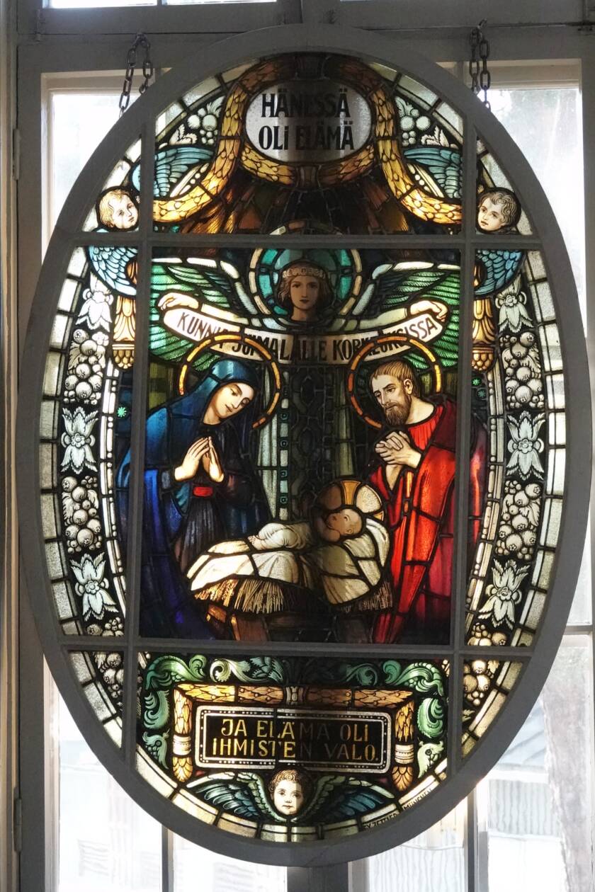 Koristeellinen vanha lasimaalaus, joka kuvaa vastasyntynyttä Jeesus-lasta, Mariaa ja Joosefia sekä enkeleitä