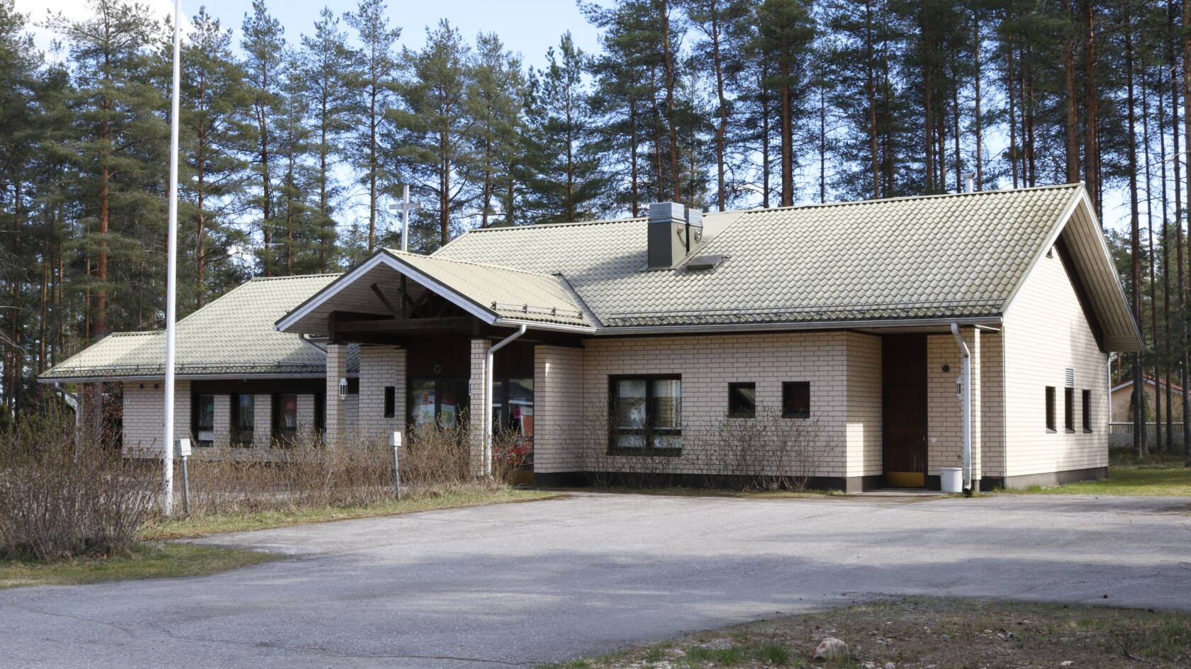 Vierumäen seurakuntatalo on yksikerroksinen tiilirakennus, jonka ympärillä on pysäköintialue ja mäntymetsää.