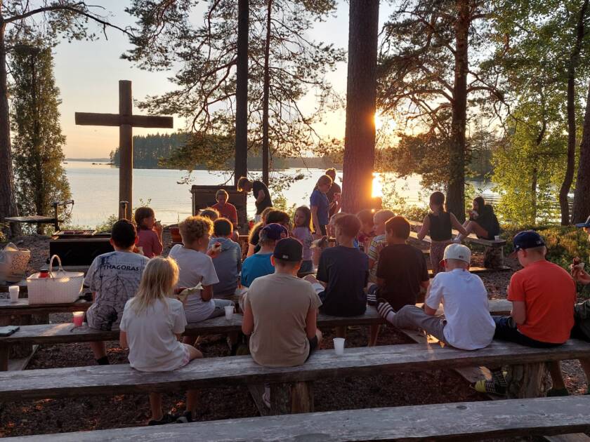 Lapsia iltanuotiolla syömässä makkaraa leirikeskuksen nuotiopaikalla.