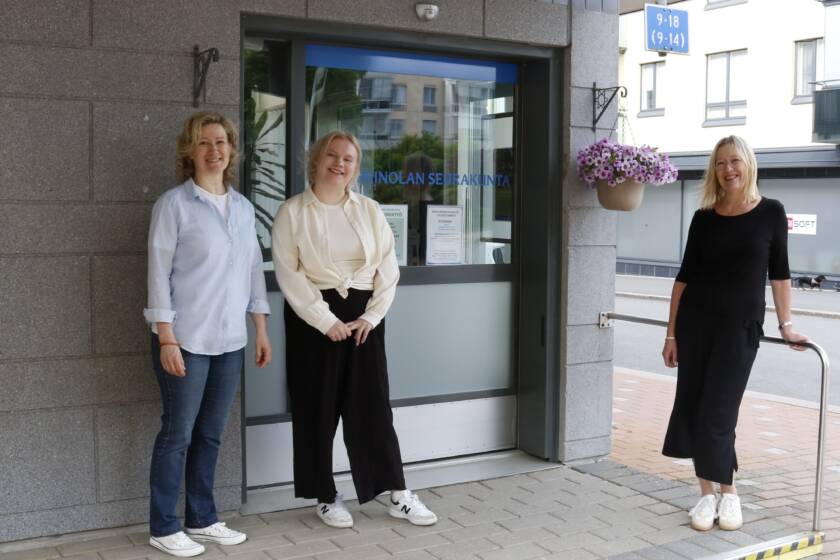 Kolme henkilöä seisoo ulko-ovella lasisen liukuoven vieressä.